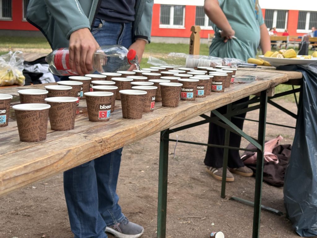 Am Getränkestand werden viele Becher mit Wasser gefüllt